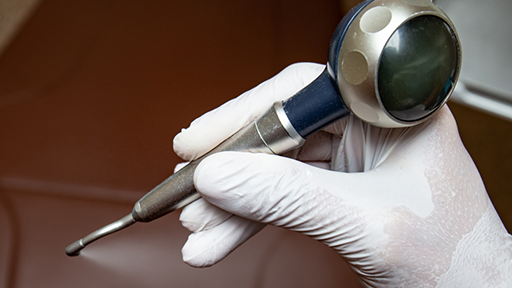 Dentist holding a pen-like air abrasion instrument