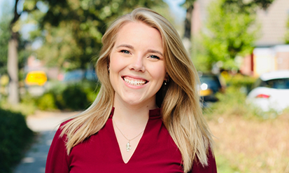 Blonde woman in a red blouse smiling outdoors