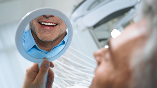 Dental patient admiring his new smile in a mirror