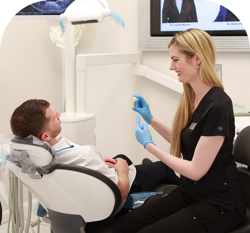 Dental team member showing a dental implant to a patient
