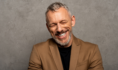 Older man smiling in a tan dinner jacket