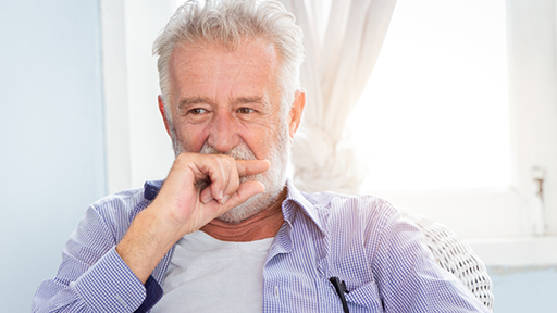 Senior man covering his mouth with the back of his hand