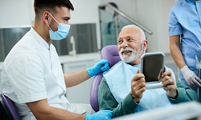 Senior man in the dental chair holding a mirror