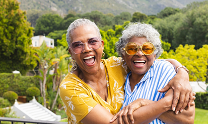 Two women laughing and hugging outdoors