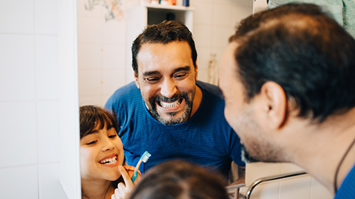 Father and daughter brushing their teeth together