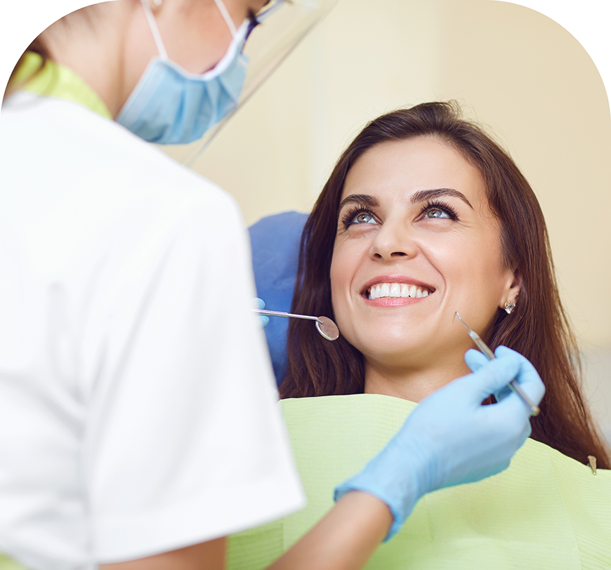 Woman in the dental chair grinning up at her dentist