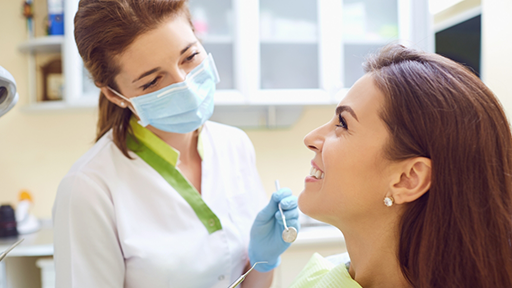 Dentist smiling at a woman in the treatment chair