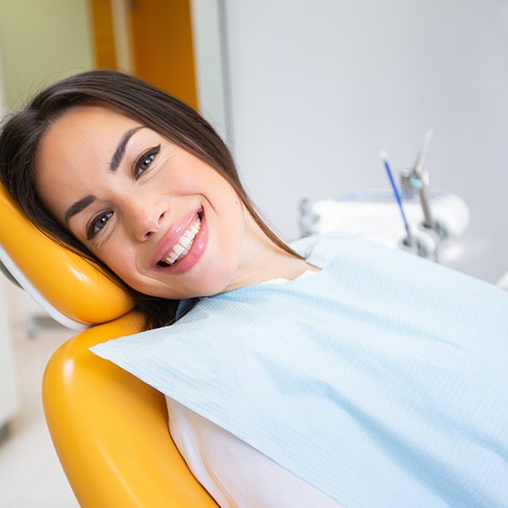 A smiling woman laying in a dentist’s chair