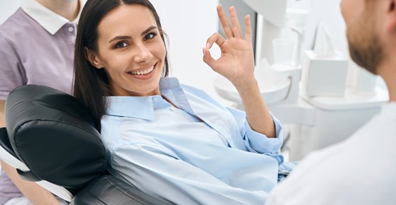 a dental patient giving the okay sign and smiling