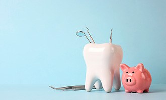 A pink piggy bank and a tooth model set against a blue background