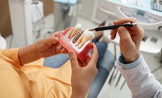 A dentist using a model to point out the parts of dental implants