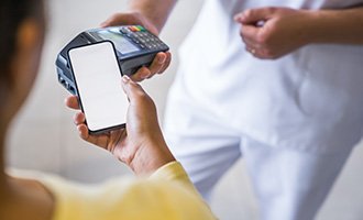 A woman using her phone to pay for her dental implants