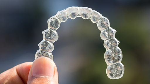 Hand holding an Invisalign aligner