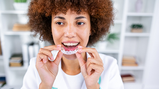 Woman holding a clear aligner close to her mouth