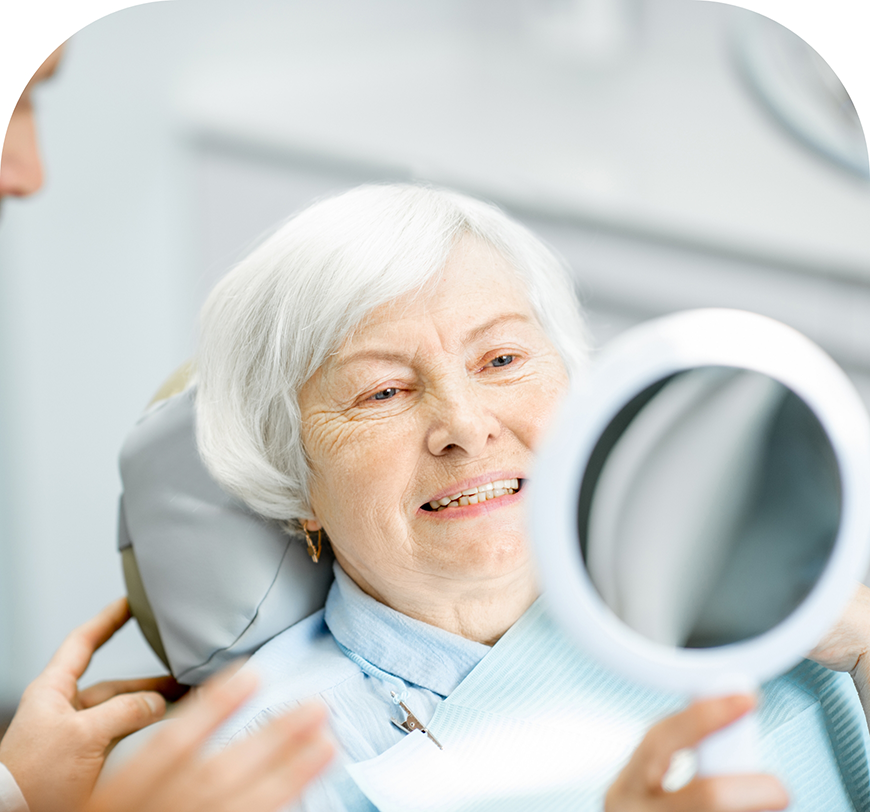 Senior woman in the dental chair admiring her smile in a mirror