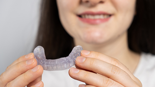Woman holding an occlusal splint tray near her smile